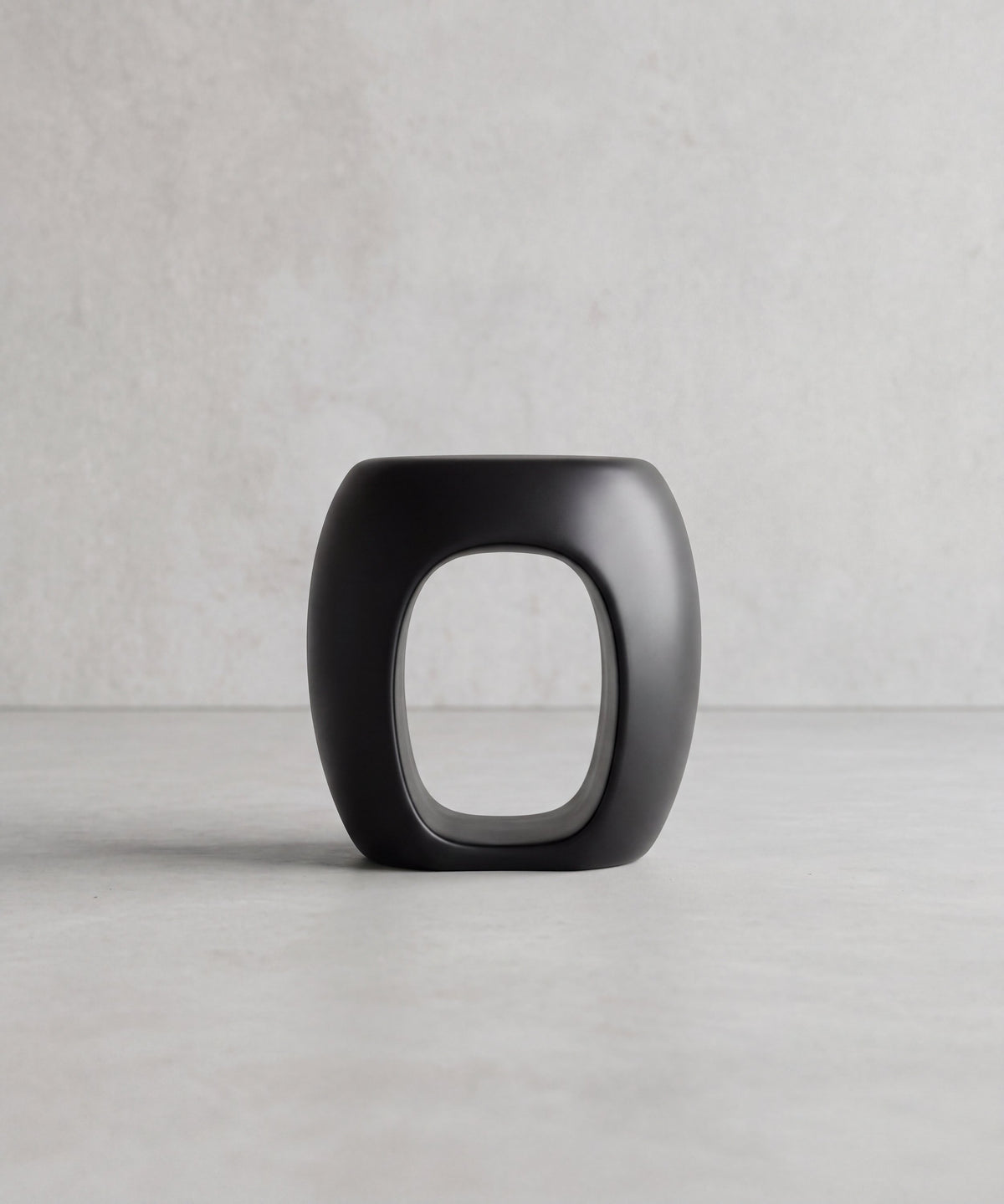 MALO Side Table – angled view of the rounded matte black form and hollow centre